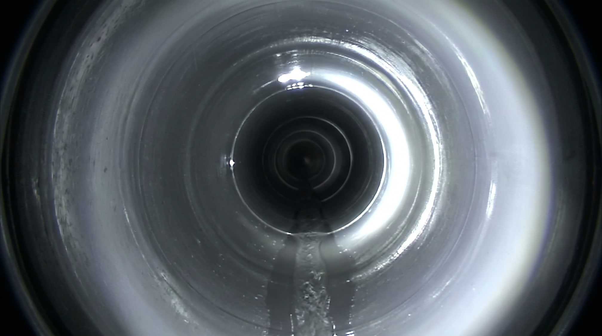 Vue de caméra : conduite nettoyée, paroi nue et filet d'eau au fond